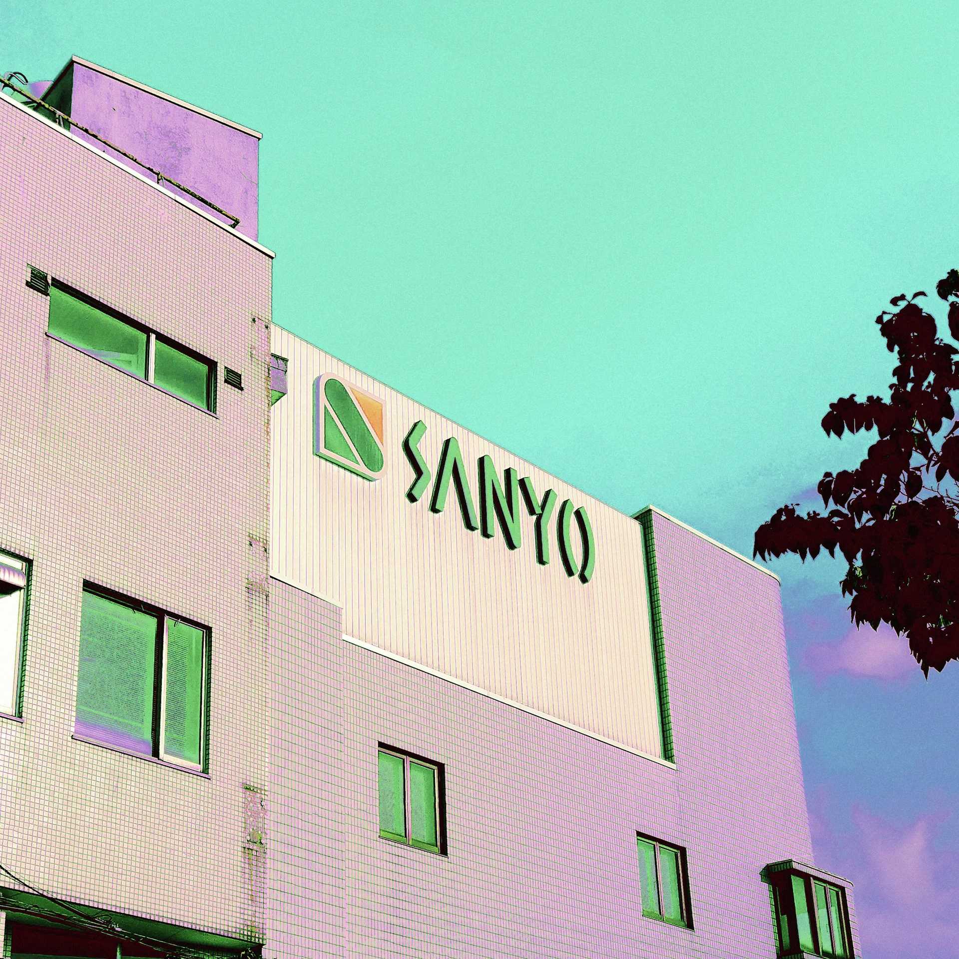 Green Sanyo lettering marks a pale pink industrial facade with green windows beneath a turquoise sky.