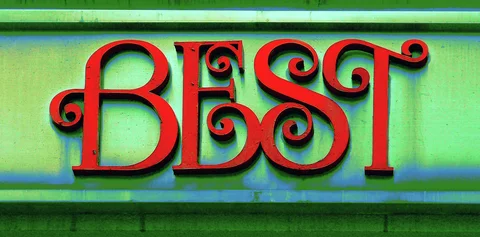 Ornate red raised letters spell Best across a pale green sign with horizontal trim.