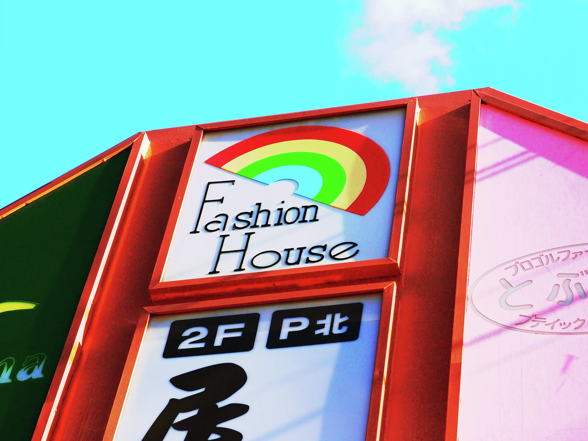 A rainbow Fashion House panel sits within red angular framing against turquoise sky.