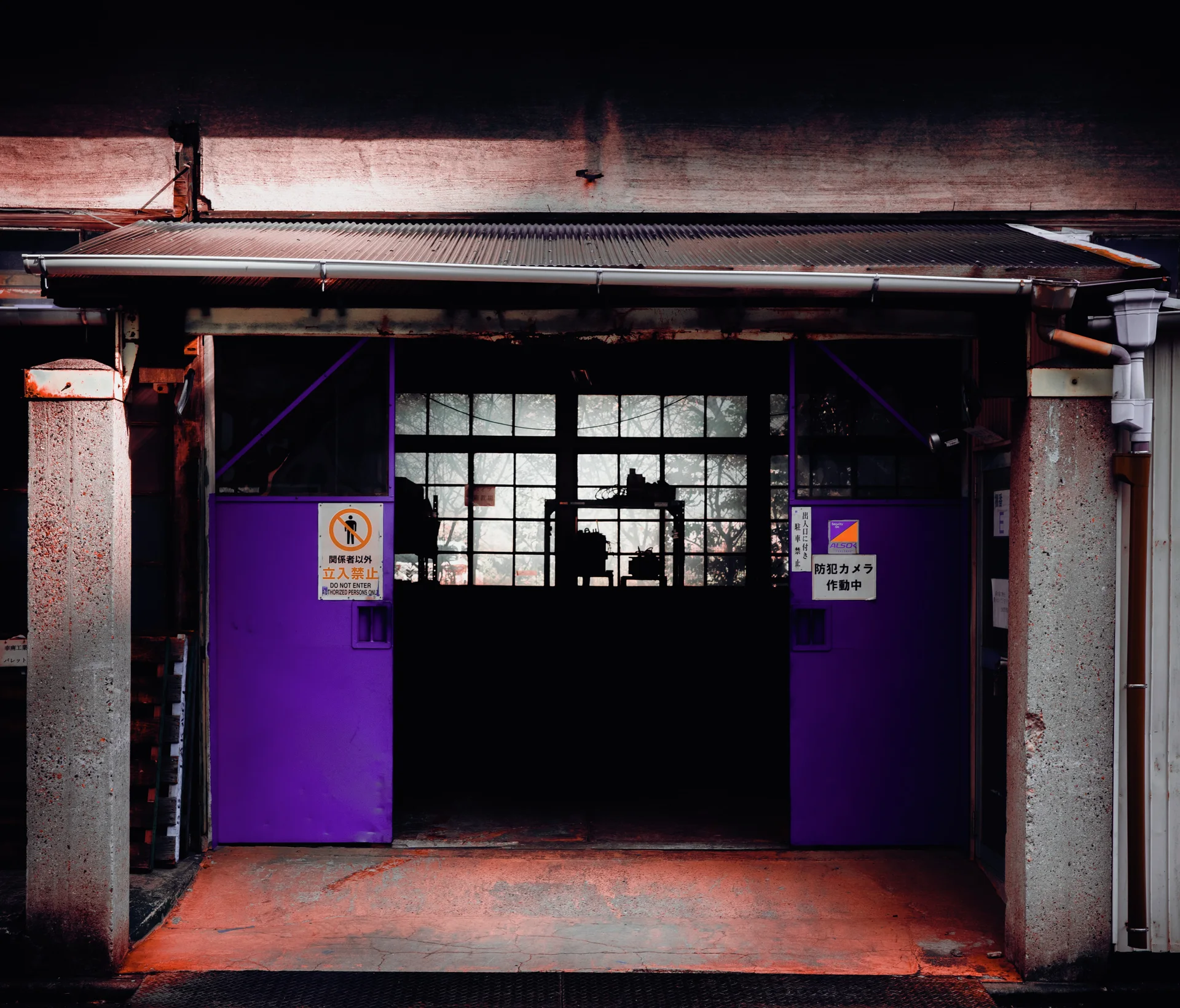 Purple double doors frame a dark entrance beneath a weathered metal awning.