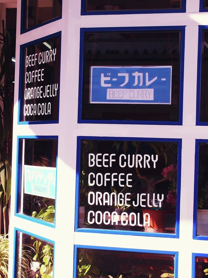 White food and drink lettering fills dark window panels separated by thick pale and blue frames.
