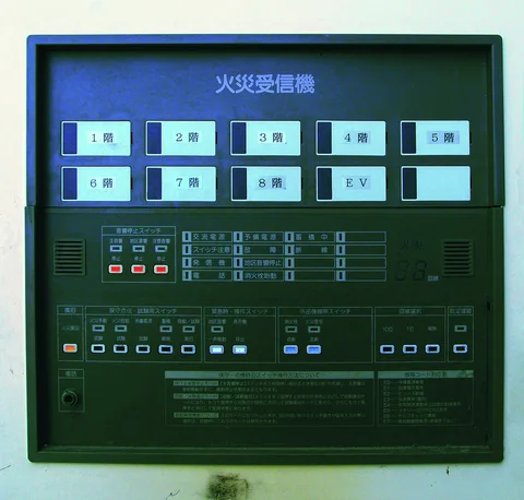 Rows of labeled buttons and small indicator lights fill a dark wall-mounted control panel.