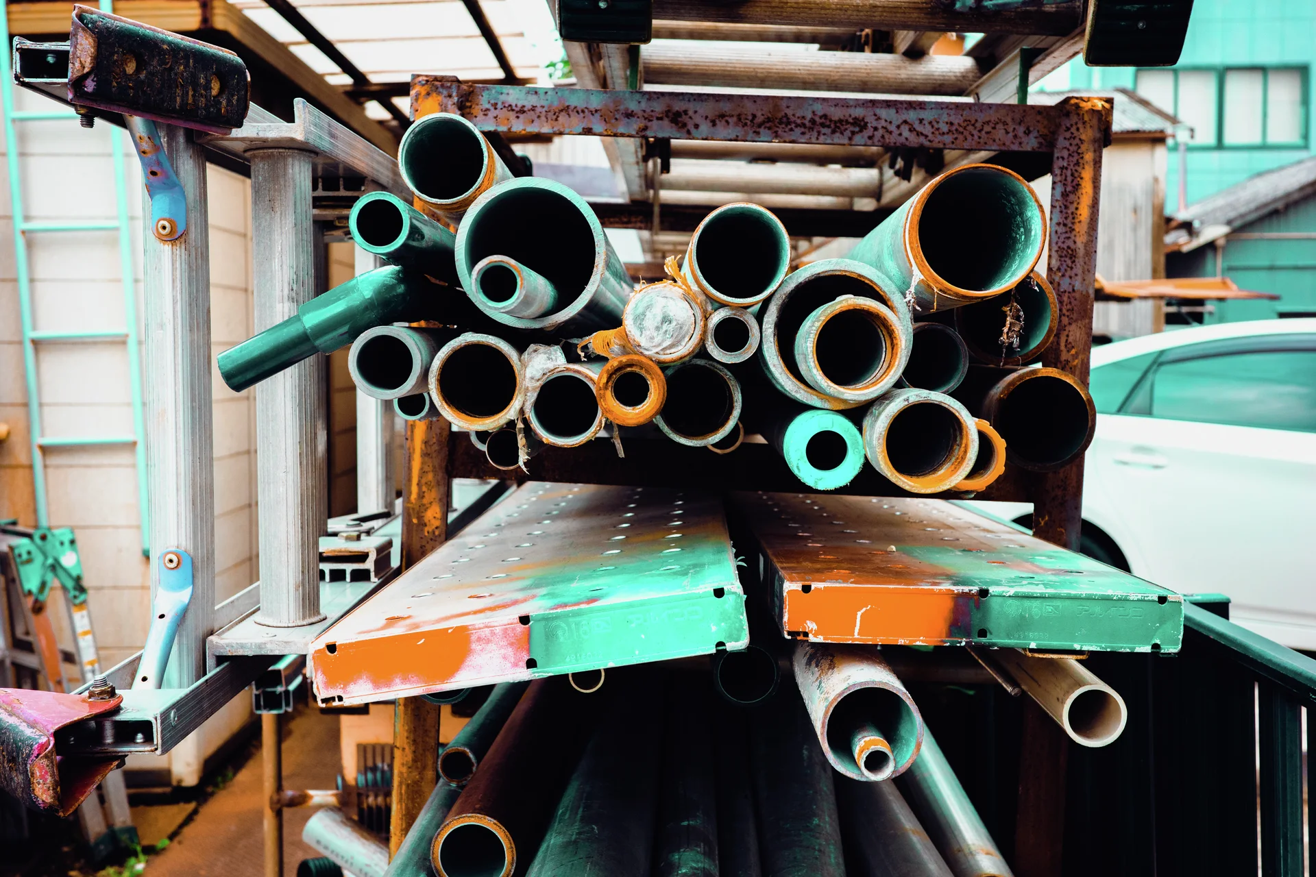 Open ends of assorted metal pipes face outward from a rack above chipped green panels.
