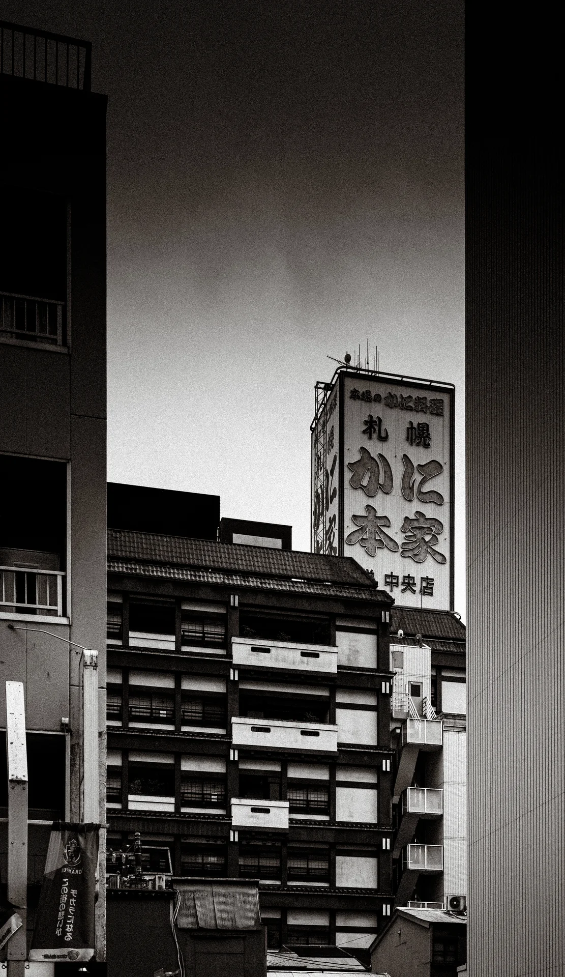 Stacks of wooden crates fill a narrow gap beside tall walls beneath a projecting restaurant sign.