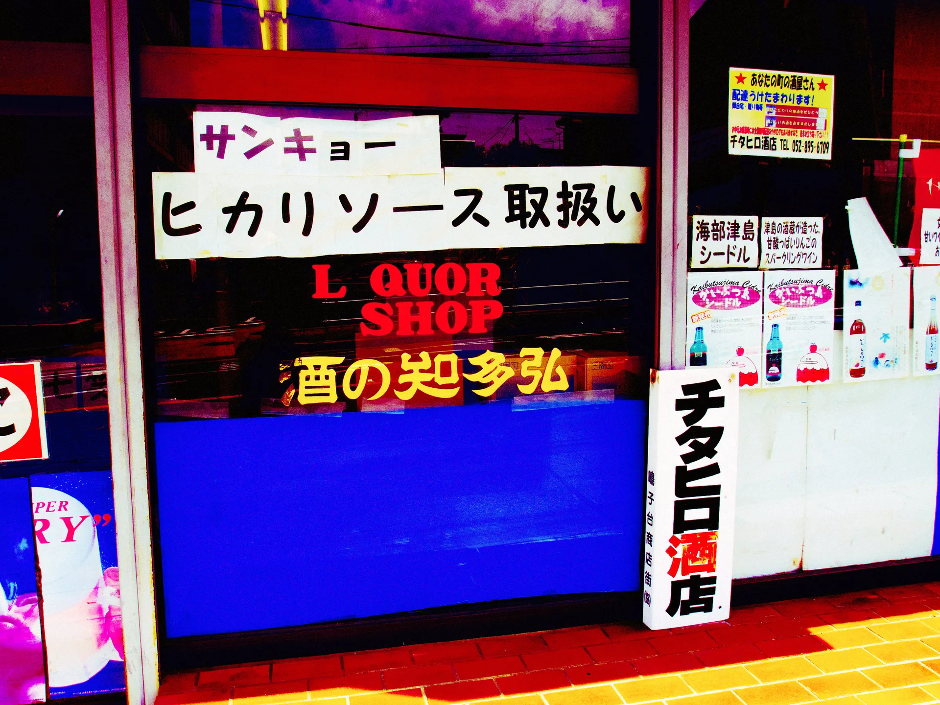 Japanese notices and red Liquor Shop lettering cover a storefront window above a vivid blue lower panel.