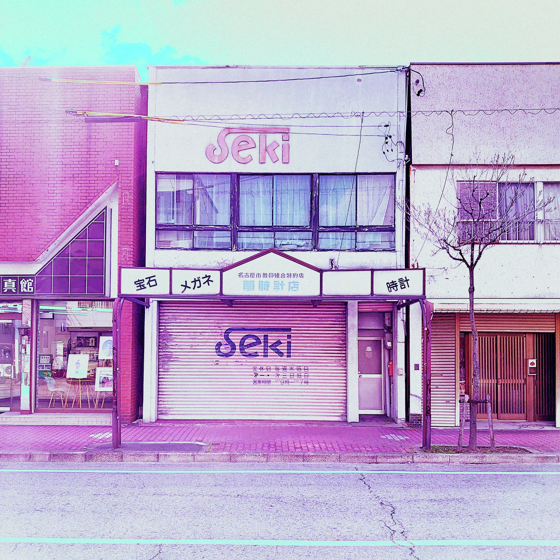 SEKI lettering appears above and across a closed shutter in a narrow pale pink storefront.