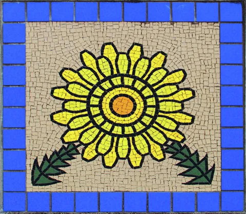 A yellow flower mosaic with green leaves sits within a bright blue square tile border.