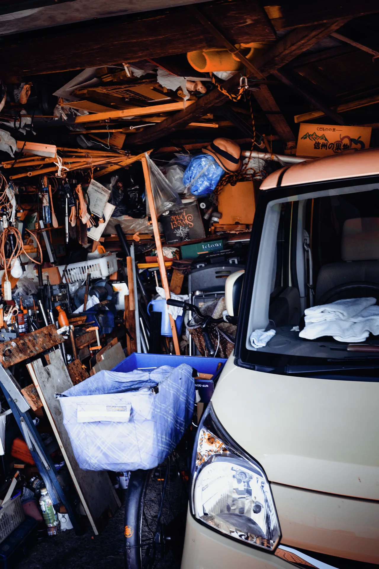 A small van fills part of a garage packed with boxes, tools, and hanging equipment.
