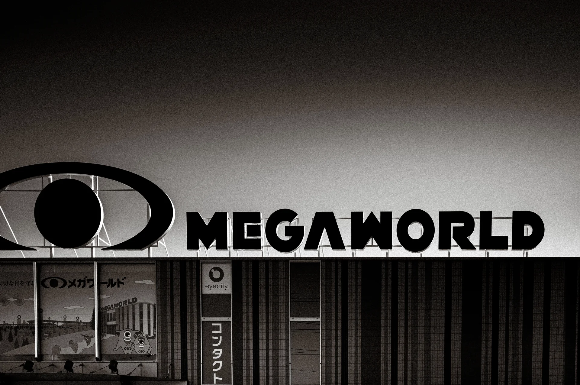 Bold MEGAWORLD lettering and an oval emblem span a storefront above striped shutters in black and white.