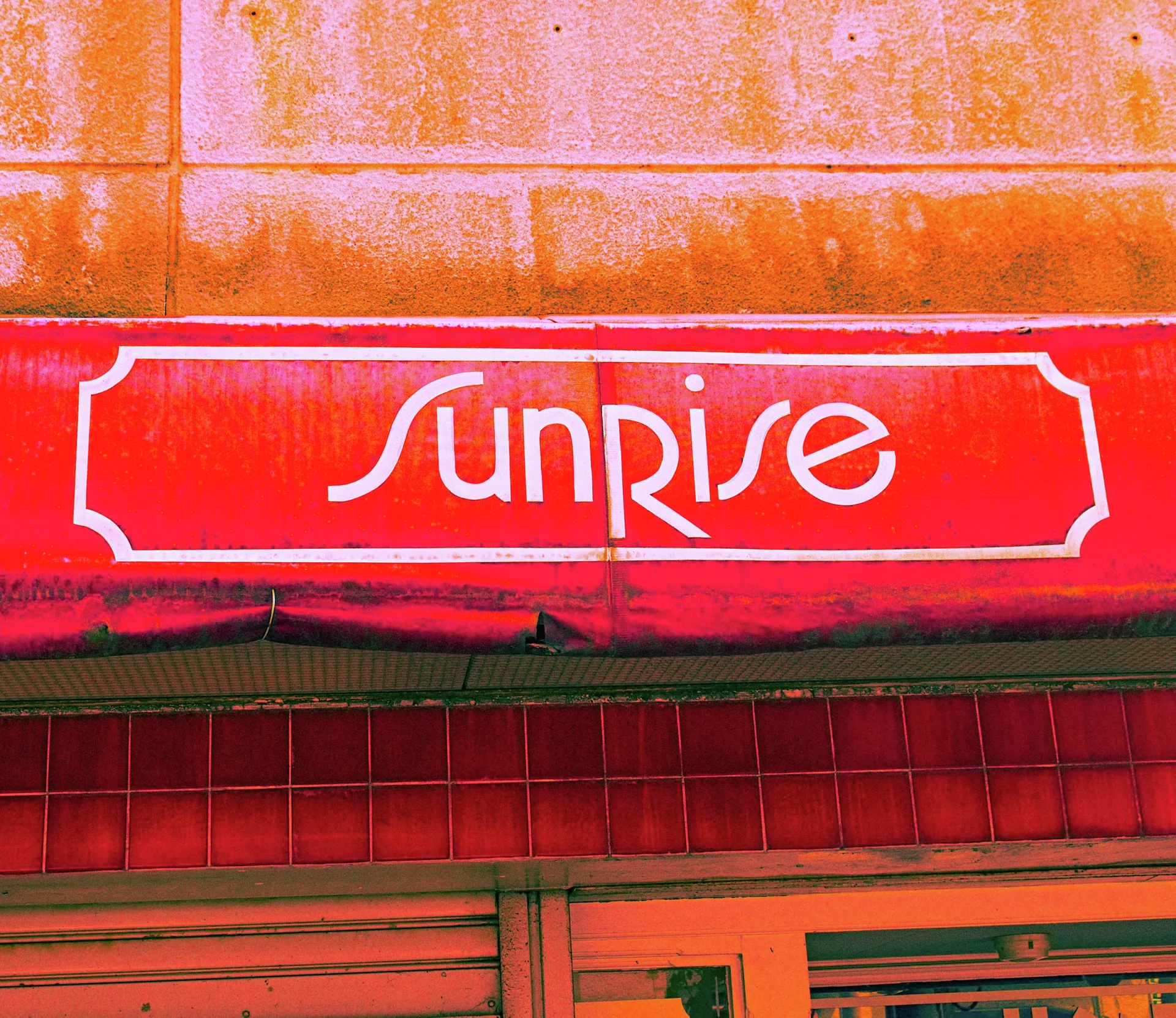 White Sunrise lettering spans a red sign beneath orange-stained exterior wall panels.