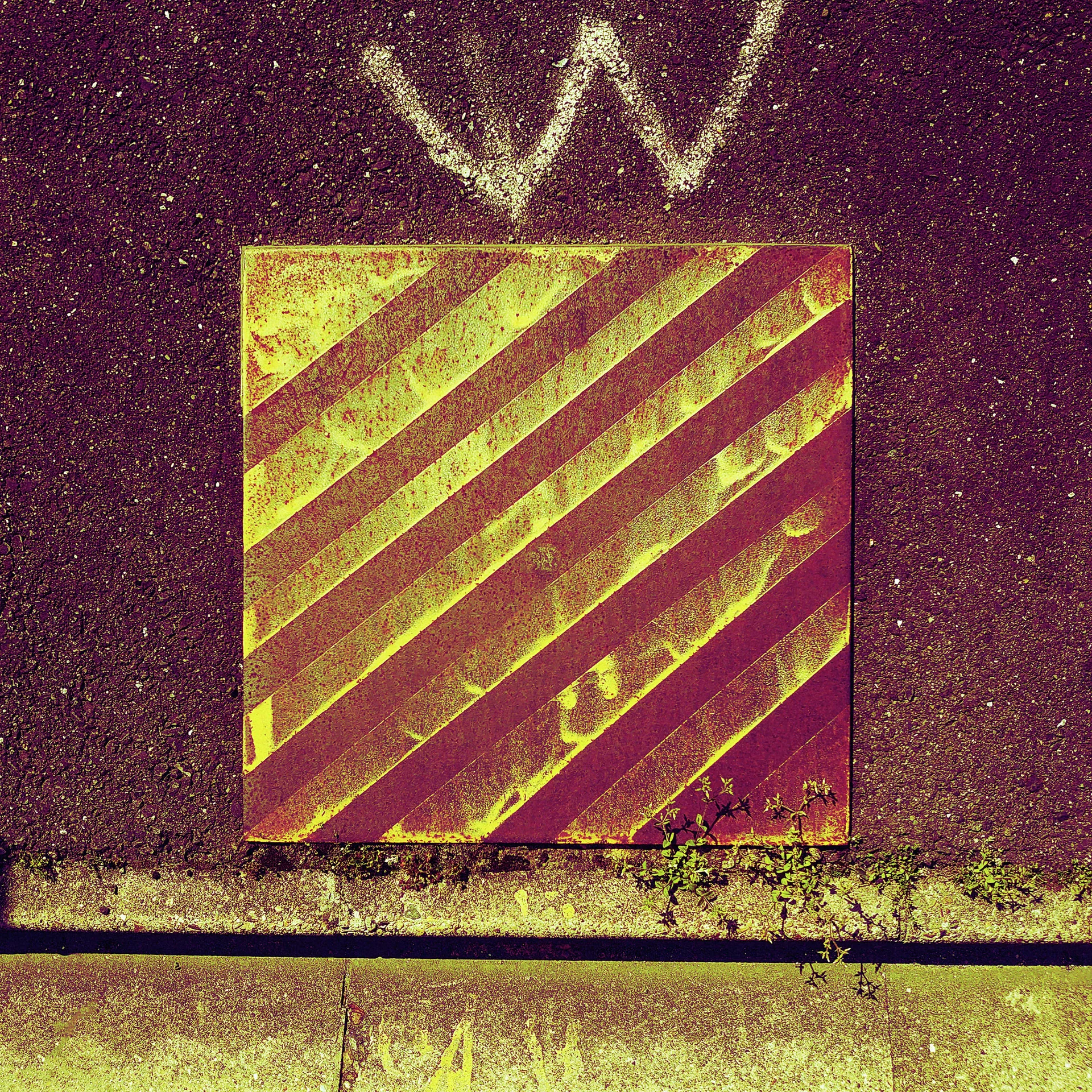 Diagonal yellow stripes fill a square panel below a pale W on a weathered burgundy wall.