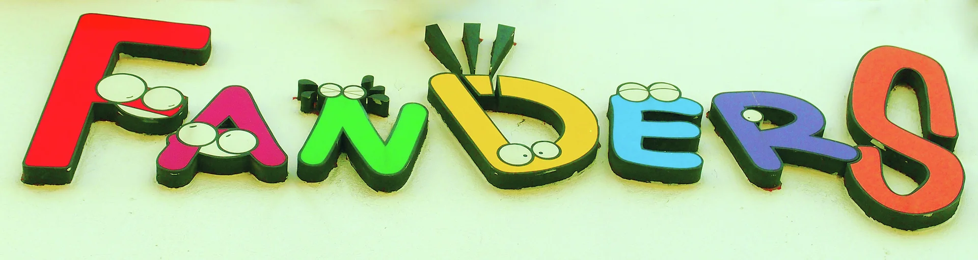 Colorful playful FANDERS letters with small cartoon eyes project from a pale wall.