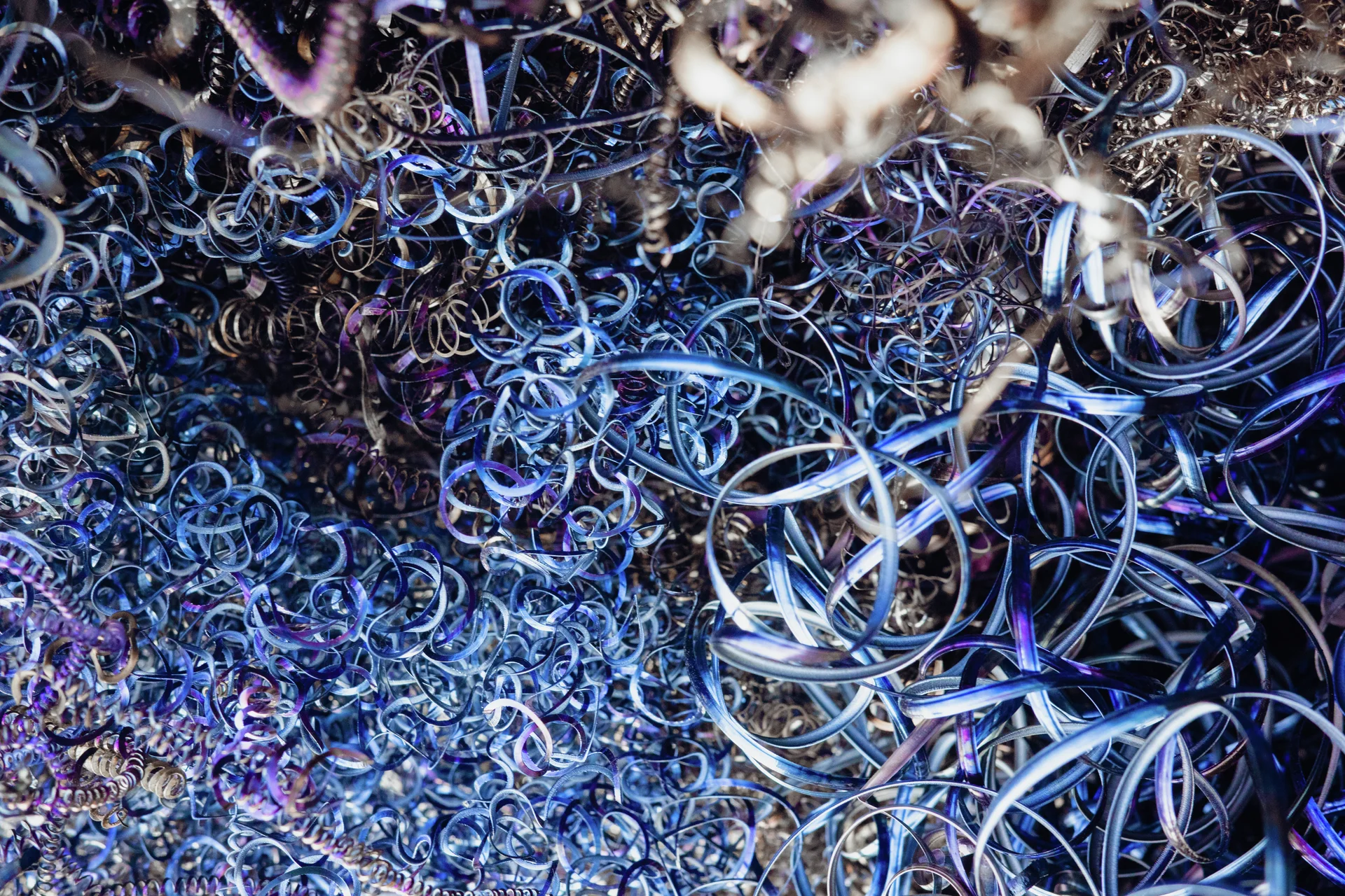 Tightly curled blue and purple metal shavings form a tangled mass of loops and spirals.