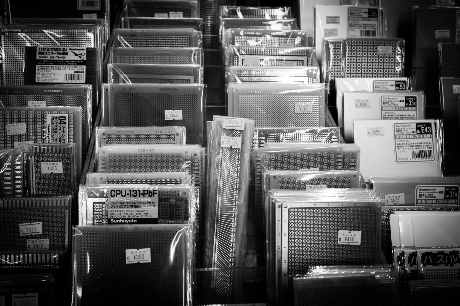 Rows of packaged rectangular grids fill angled shop display racks in a black and white view.