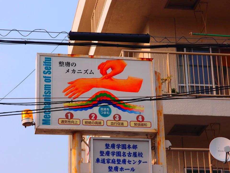 An orange arm illustration and colored wave diagram fill a projecting sign crossed by overhead cables.