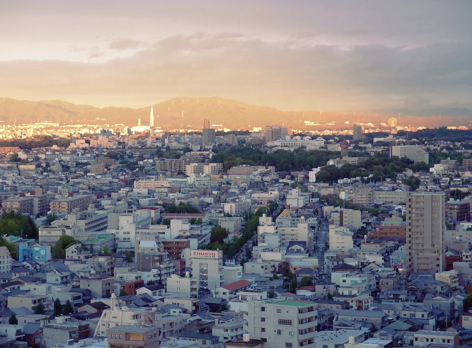 Warm light touches distant mountains above a dense foreground of white and gray city buildings.