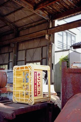 A yellow-framed sign rests among rusty metal equipment inside an open industrial shed.