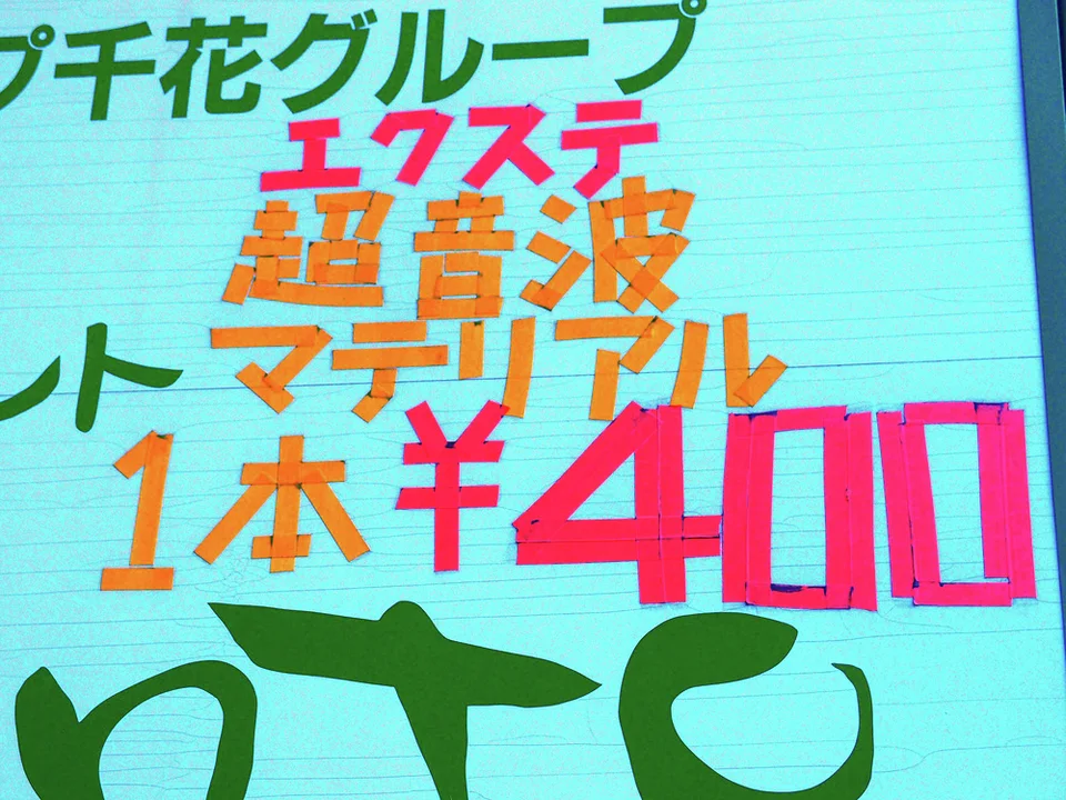 Large pink price numerals and orange characters fill a turquoise wall beneath green lettering.