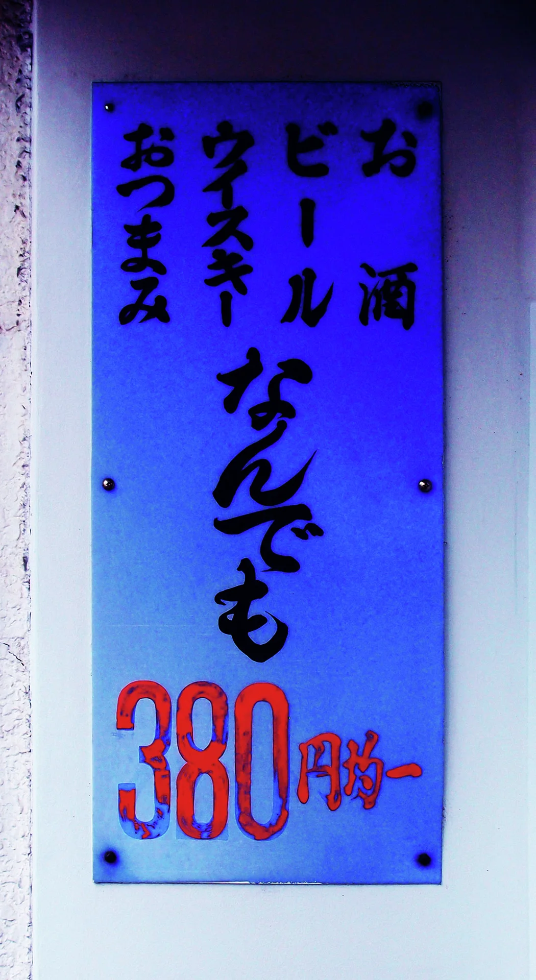 Dark vertical lettering and large red numerals fill a blue rectangular sign mounted on a pale wall.
