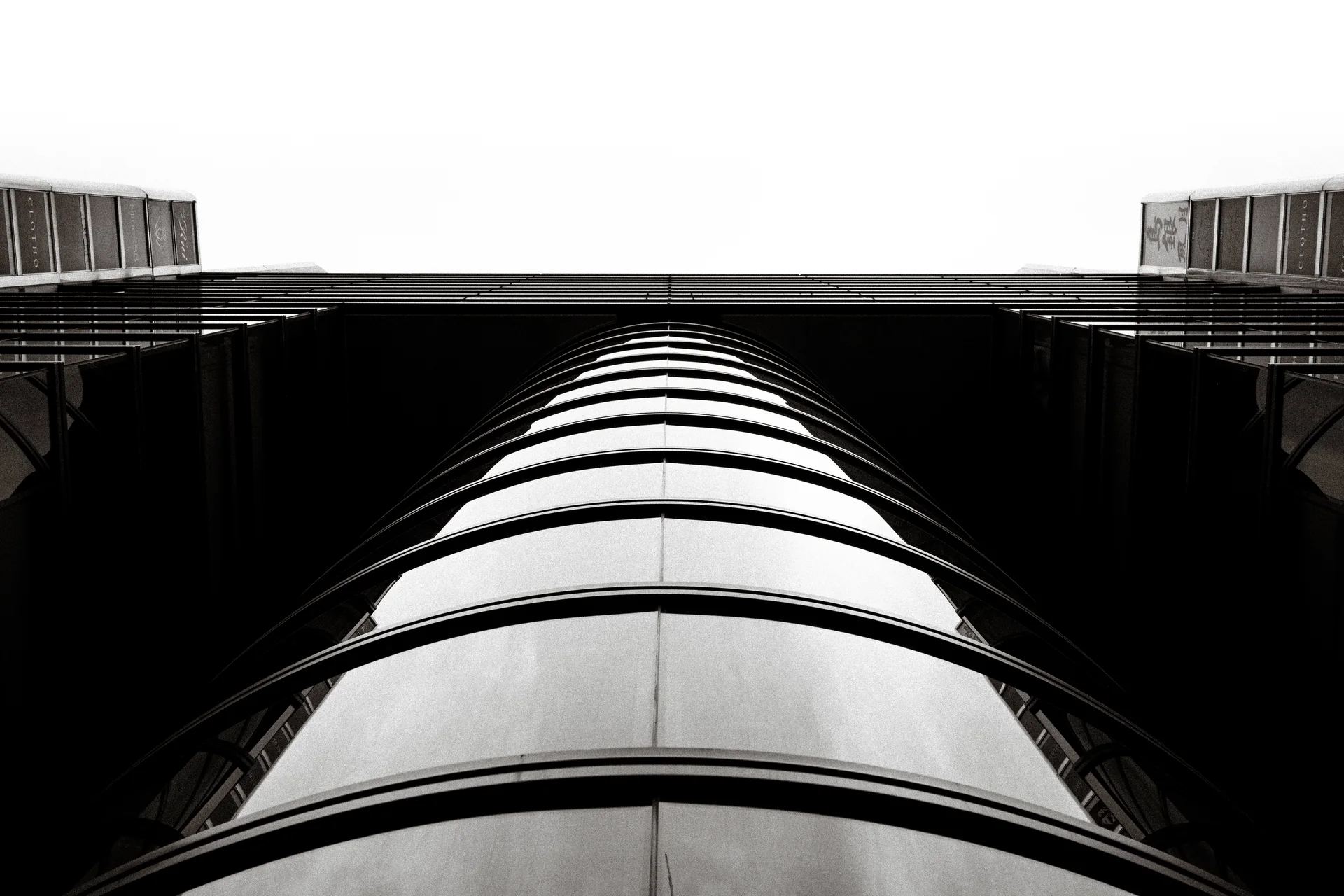 Repeating dark horizontal bands wrap a rounded tower viewed steeply upward in monochrome.