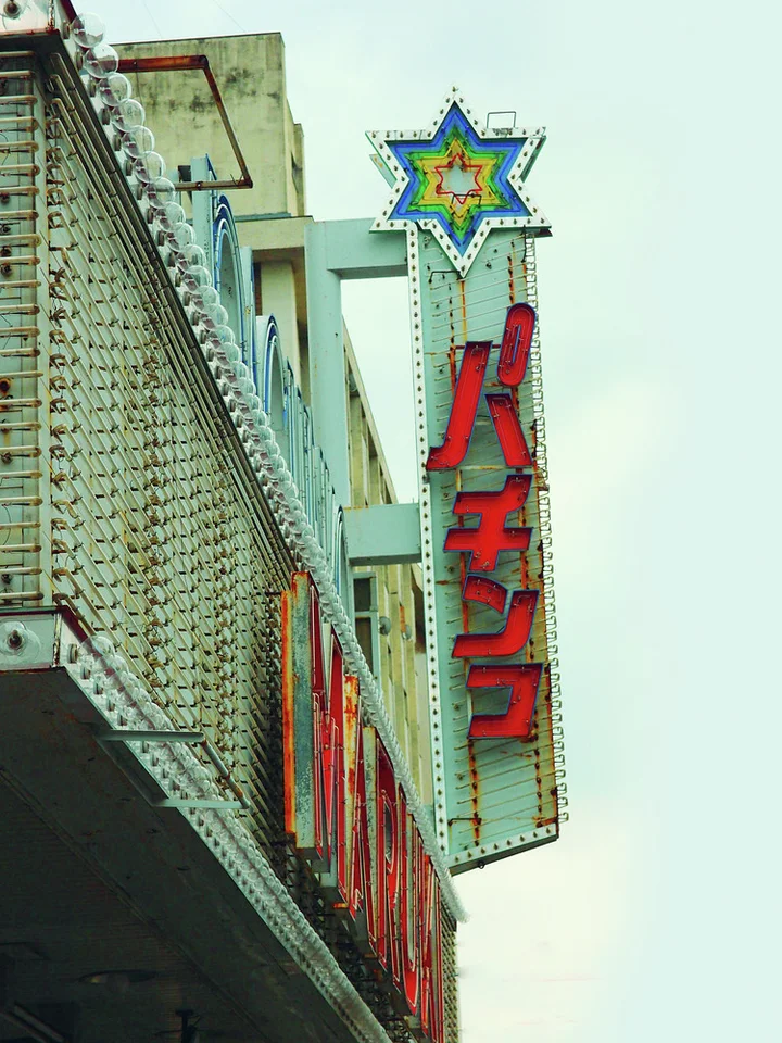 A star-shaped ornament crowns a tall projecting sign with large red Japanese letters beside a textured facade.