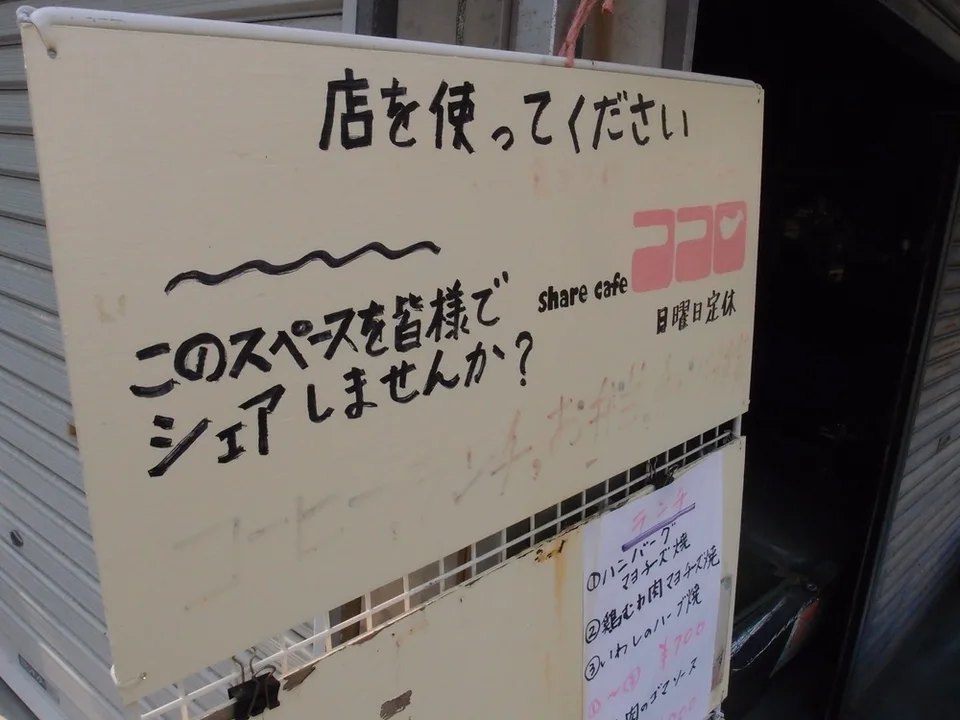 Black Japanese lettering covers a pale freestanding cafe board with a smaller clipped notice below.