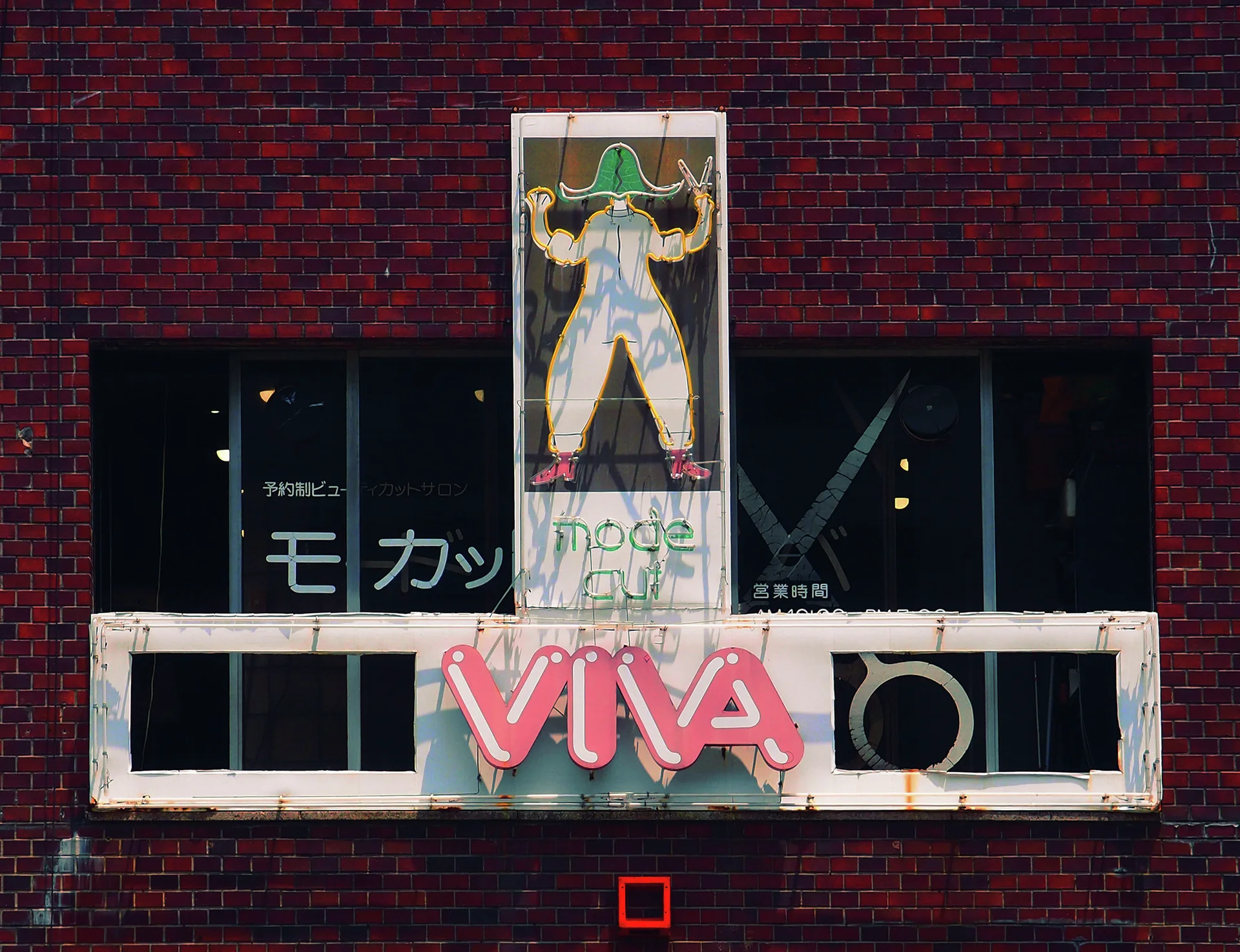 A colorful outlined figure and large pink VIVA letters decorate a weathered sign on a brick building.