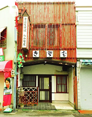 Tall red wooden slats screen the upper floor above a small recessed shop entrance.