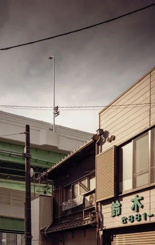 Low storefront roofs and upper windows rise beneath crossing utility wires and a tall antenna against gray clouds.