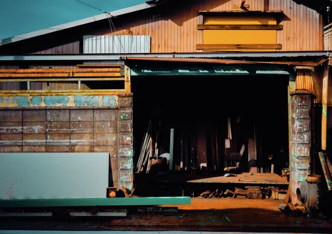 Yellow trim tops an open workshop entrance containing upright boards and dark equipment.