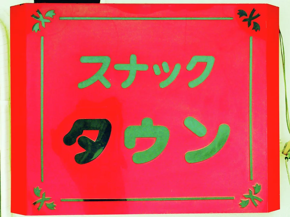 Green and black Japanese characters fill a bright red panel bordered by thin decorative green lines.
