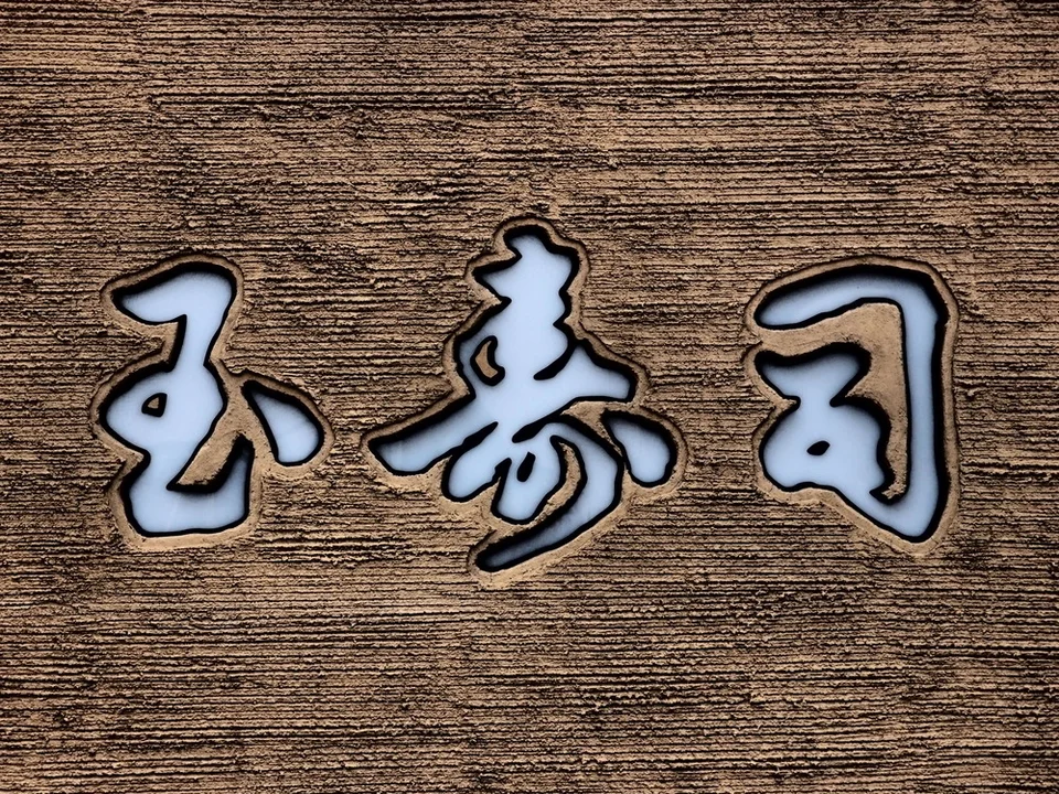 Three pale inset characters outlined in dark trim mark a textured brown wall.