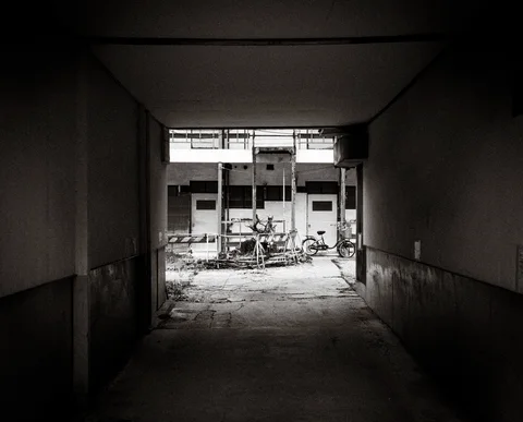A dark rectangular passage frames a bright courtyard with bicycles and pale building walls.