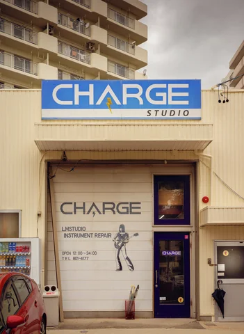 A blue studio sign crowns a closed cream shutter decorated with lettering and a dancing figure.