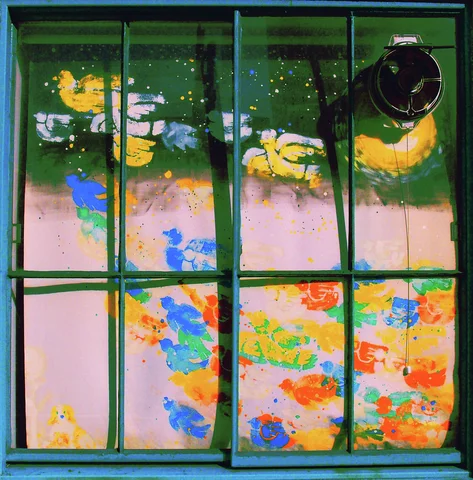 Green window frames divide glass mottled with yellow, blue, orange, and pale patches.