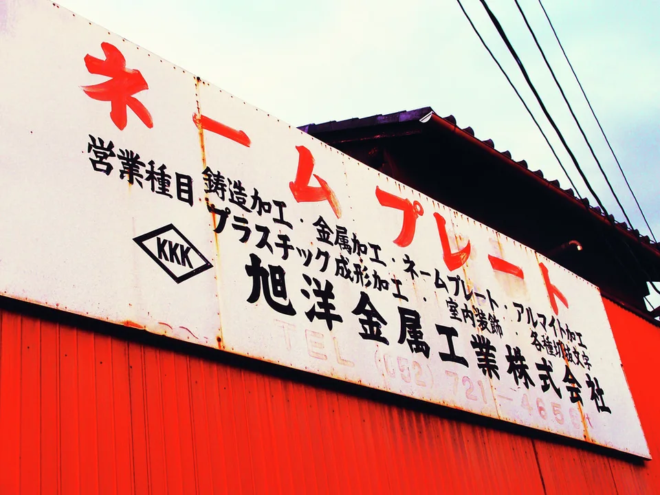 A broad white industrial sign with red and black characters tops bright red corrugated siding.