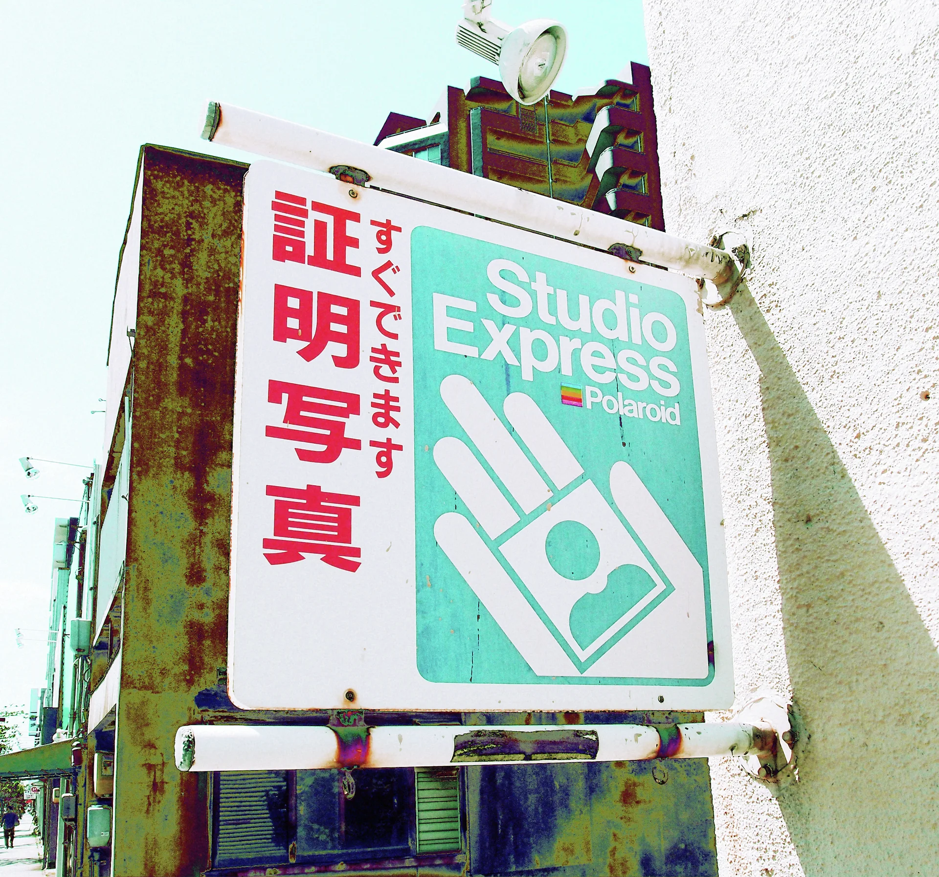A weathered Studio Express sign displays a white hand-and-card graphic beside large red Japanese characters.