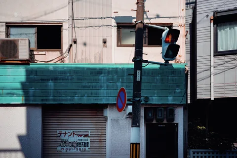 A turquoise awning spans a shuttered storefront beside a traffic signal showing red.
