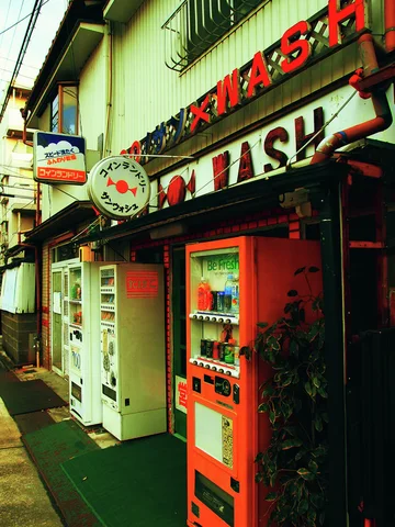 Red and white vending machines line a narrow storefront beneath large red and black lettering.
