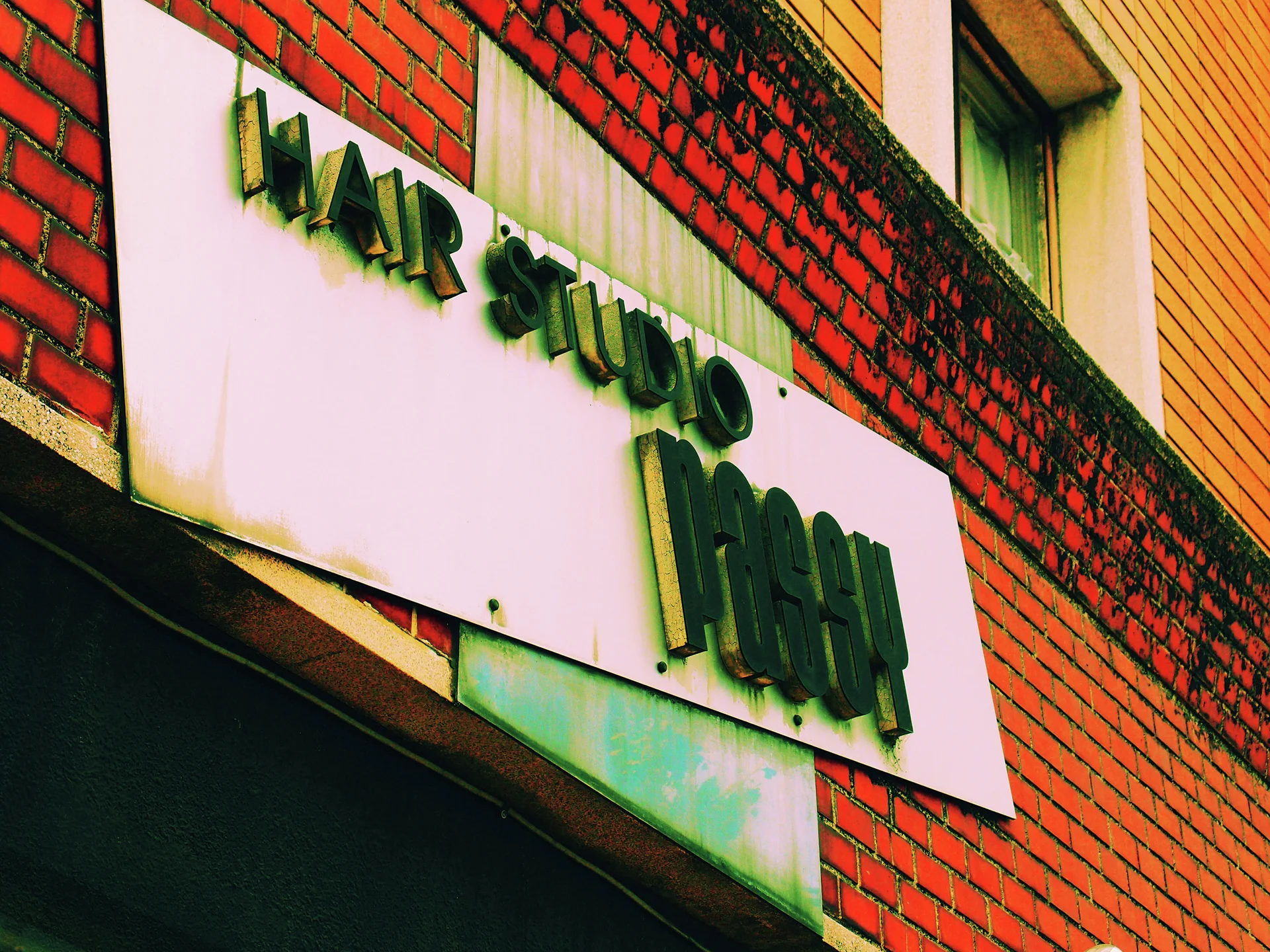 Raised dark lettering on a pale rectangular sign contrasts with the surrounding red brick facade.