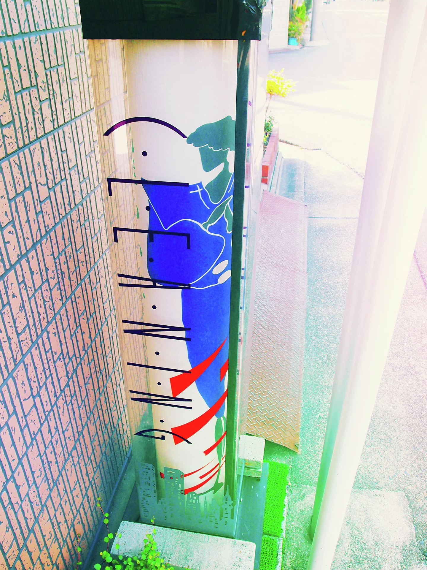A barber pole with red and blue stripes stands beside tiles in bright glare.