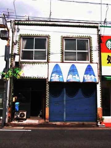 Three blue triangular painted panels sit above closed blue shutters beneath two upper windows.