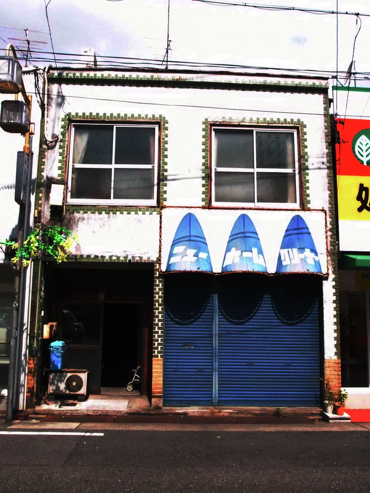Three blue triangular painted panels sit above closed blue shutters beneath two upper windows.