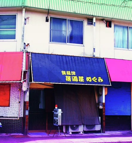 A dark blue awning and curtain shade an entrance between pink walls and blue shutters.