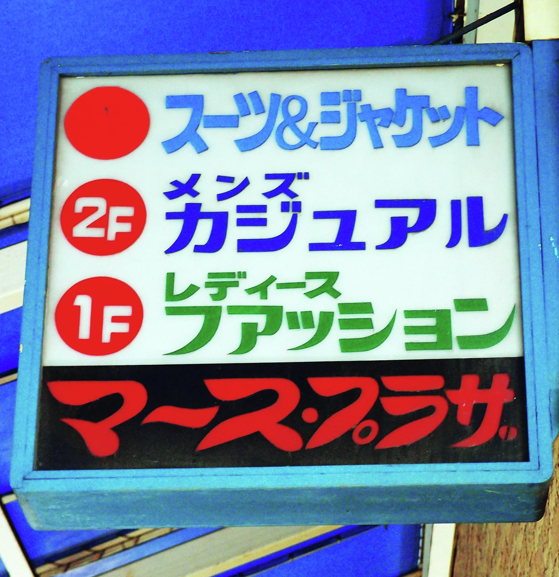 A blue-framed sign displays blue, green, and red lettering with circular floor markers.