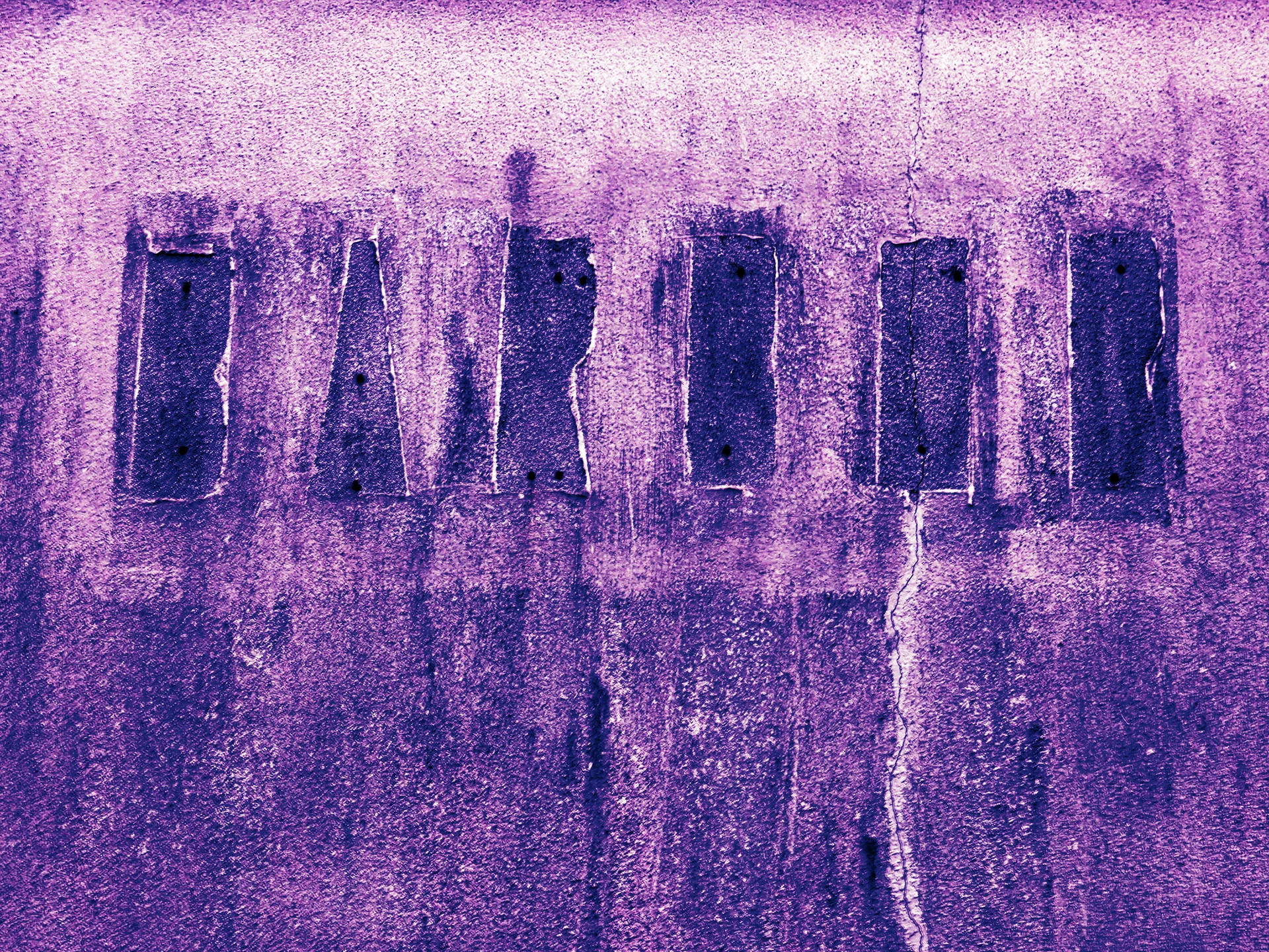 Faded dark lettering crosses a cracked, rough purple-toned wall streaked with vertical stains.