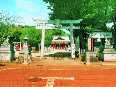 A pale gateway frames a tree-filled courtyard with stone lanterns and a red building beyond.