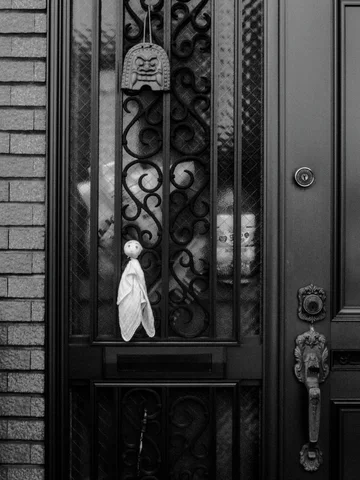 Decorative black scrollwork covers a glass entrance door with several hanging ornaments in black and white.