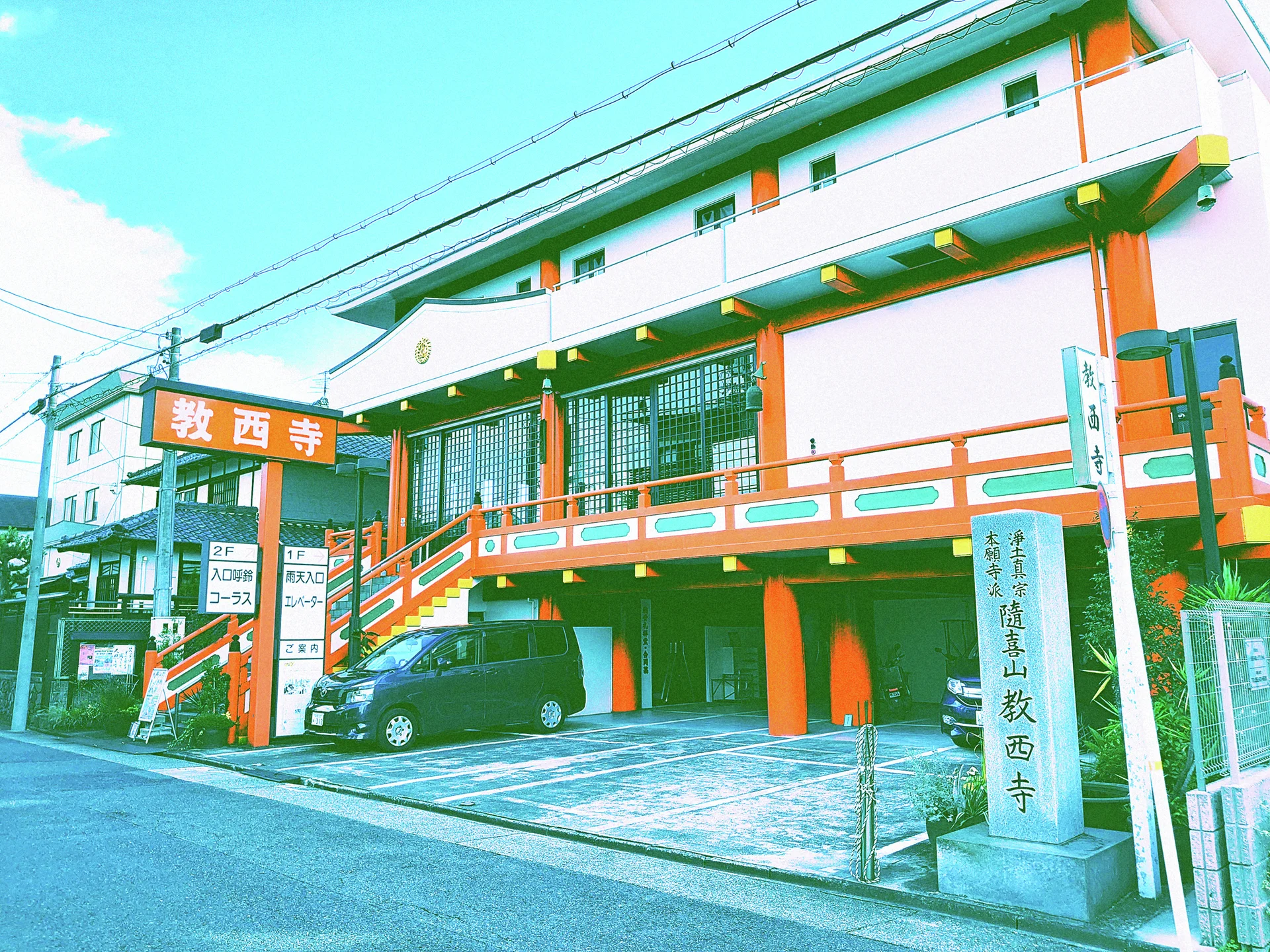 Orange columns and railings frame exterior stairs and covered parking beneath a white multi-story building.
