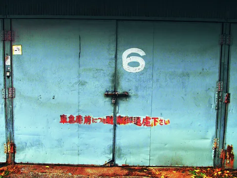 A white numeral six marks locked turquoise double doors with red Japanese lettering and rusty lower edges.